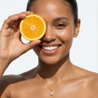 Thumbnail for Astra Teardrop Necklace by Brother & Sisters worn by a smiling woman holding an orange slice.