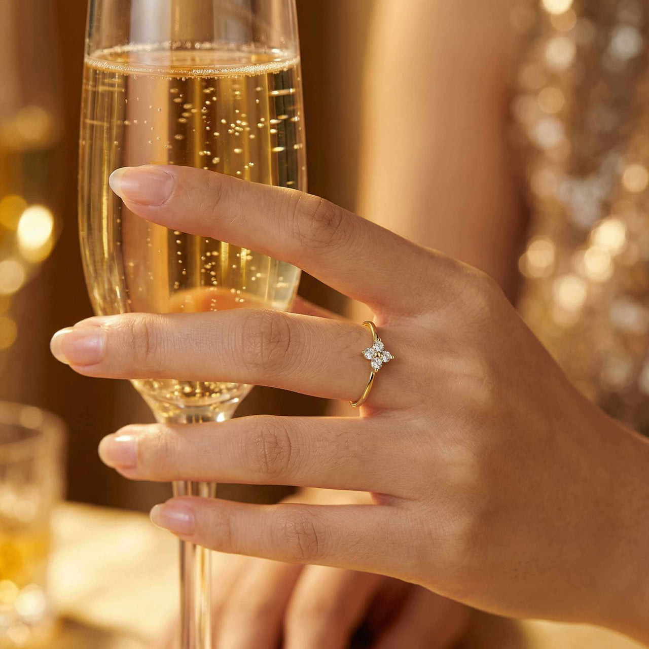 Crystal Flower Ring worn on a hand holding a champagne flute, featuring a tiny crystal flower and delicate band by Brother & Sisters.