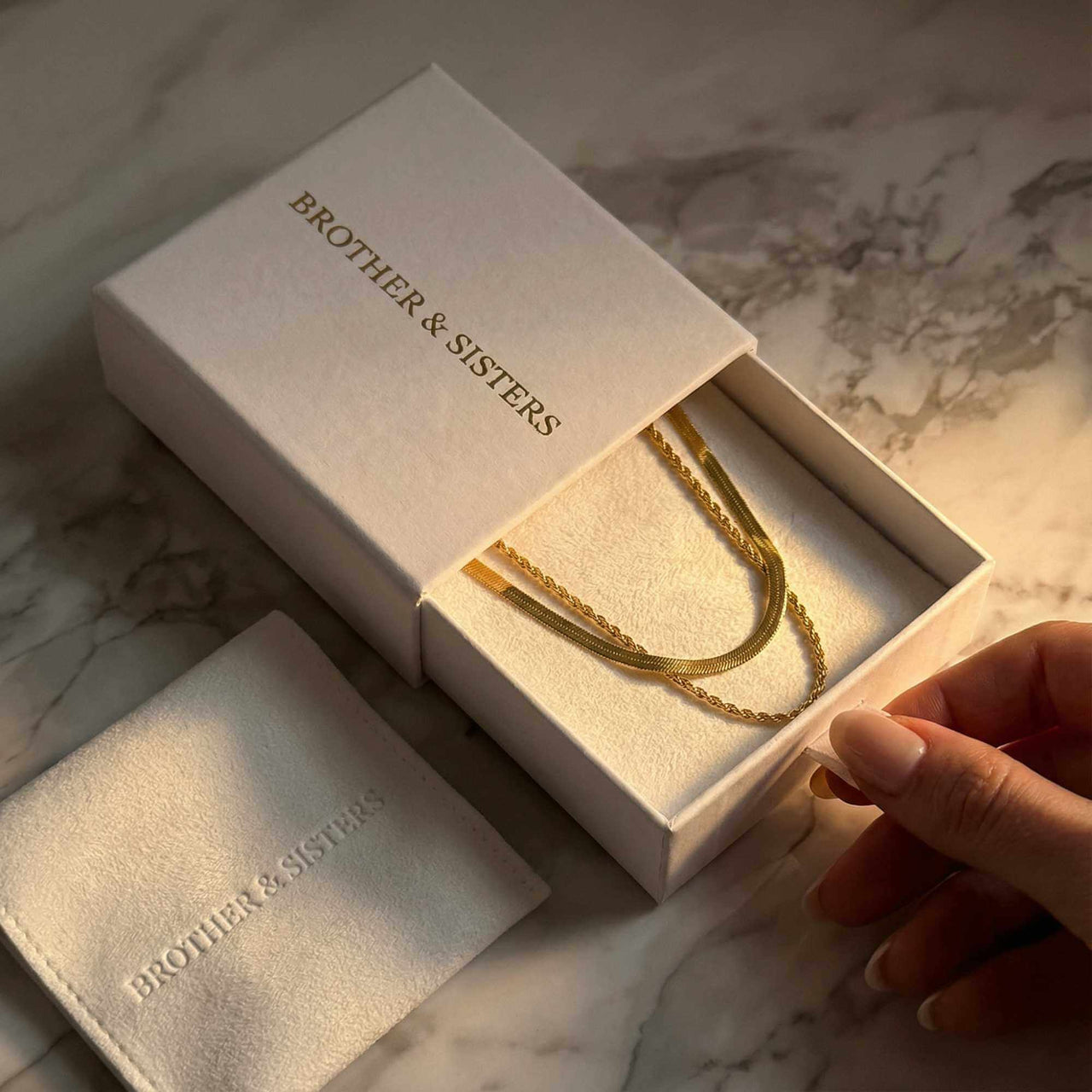 The Double Luxe necklace by Brother & Sisters in elegant packaging, showcasing sophisticated double-chain design.
