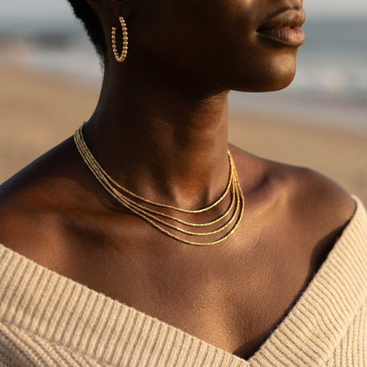 Riviera Layered Choker by Brother & Sisters, featuring four delicate chains in gold, styled with casual beach wear.