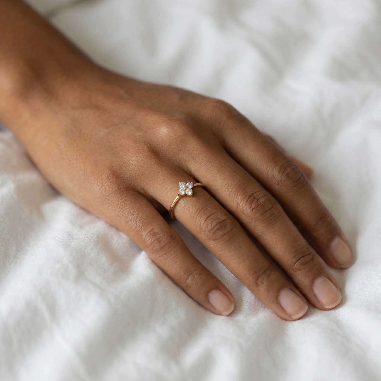 Crystal Flower Ring on a hand, featuring a miniature four-leaf crystal flower and delicate band by Brother & Sisters.