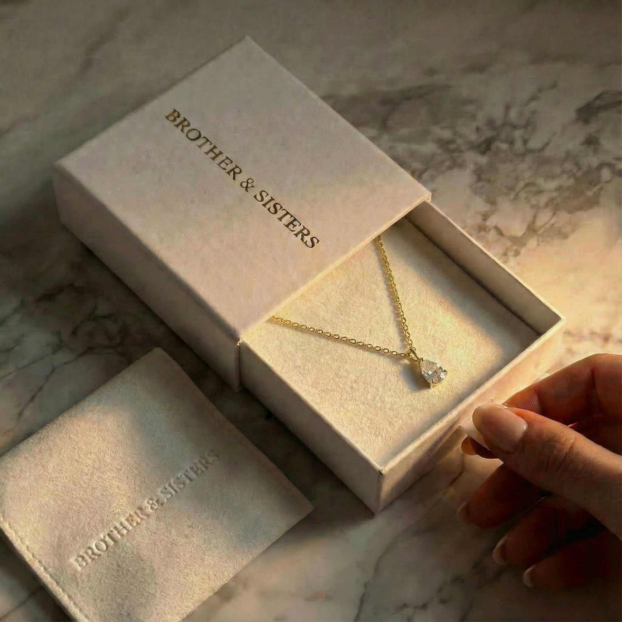 Astra Teardrop Necklace displayed in a Brother & Sisters box with soft lighting.