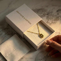 Thumbnail for Starlight Pendant Necklace in a gift box by Brother & Sisters, showcasing polished gold tag with starburst and zirconia.