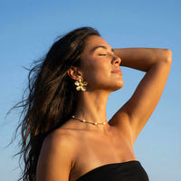 Thumbnail for Dainty Pearl Choker worn with floral earrings by Brother & Sisters, showcasing elegance against a clear blue sky.