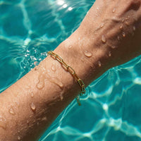 Thumbnail for Paperclip Chain Bracelet on a wet wrist, showcasing simple links and 18K gold finish by Brother & Sisters.