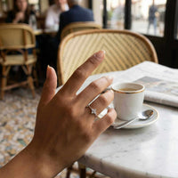 Thumbnail for Crystal Flower Ring worn on a hand holding a coffee cup, showcasing its delicate design by Brother & Sisters.