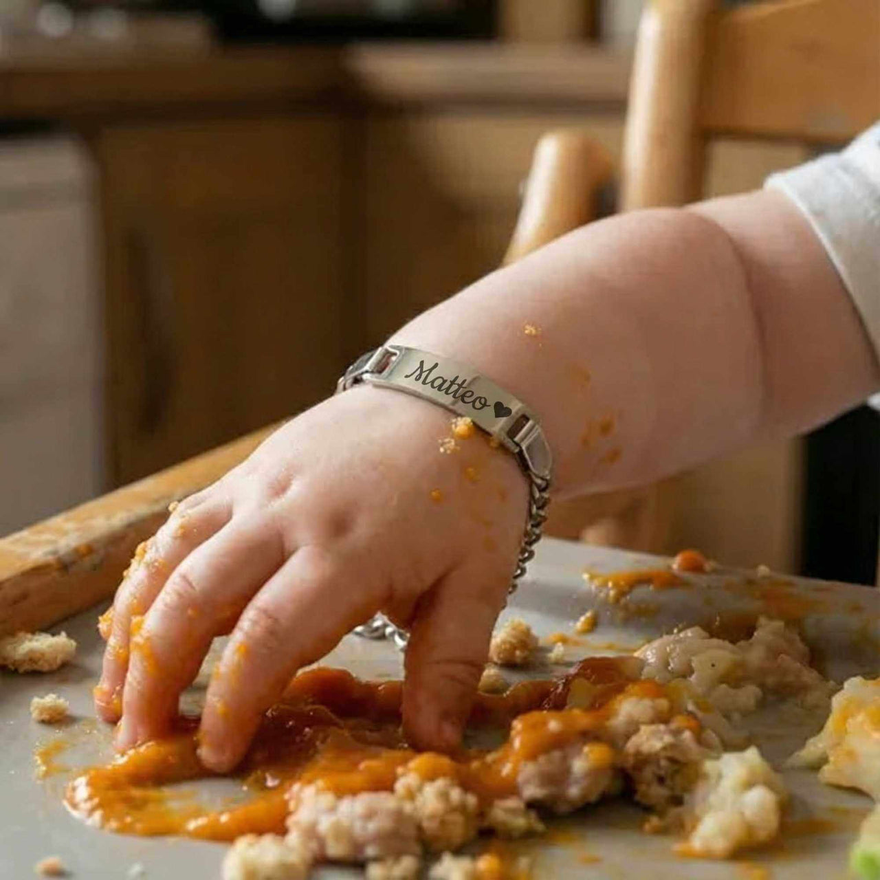 Infant Bracelet on a baby's hand covered in food, personalized for Matteo by Brother & Sisters.