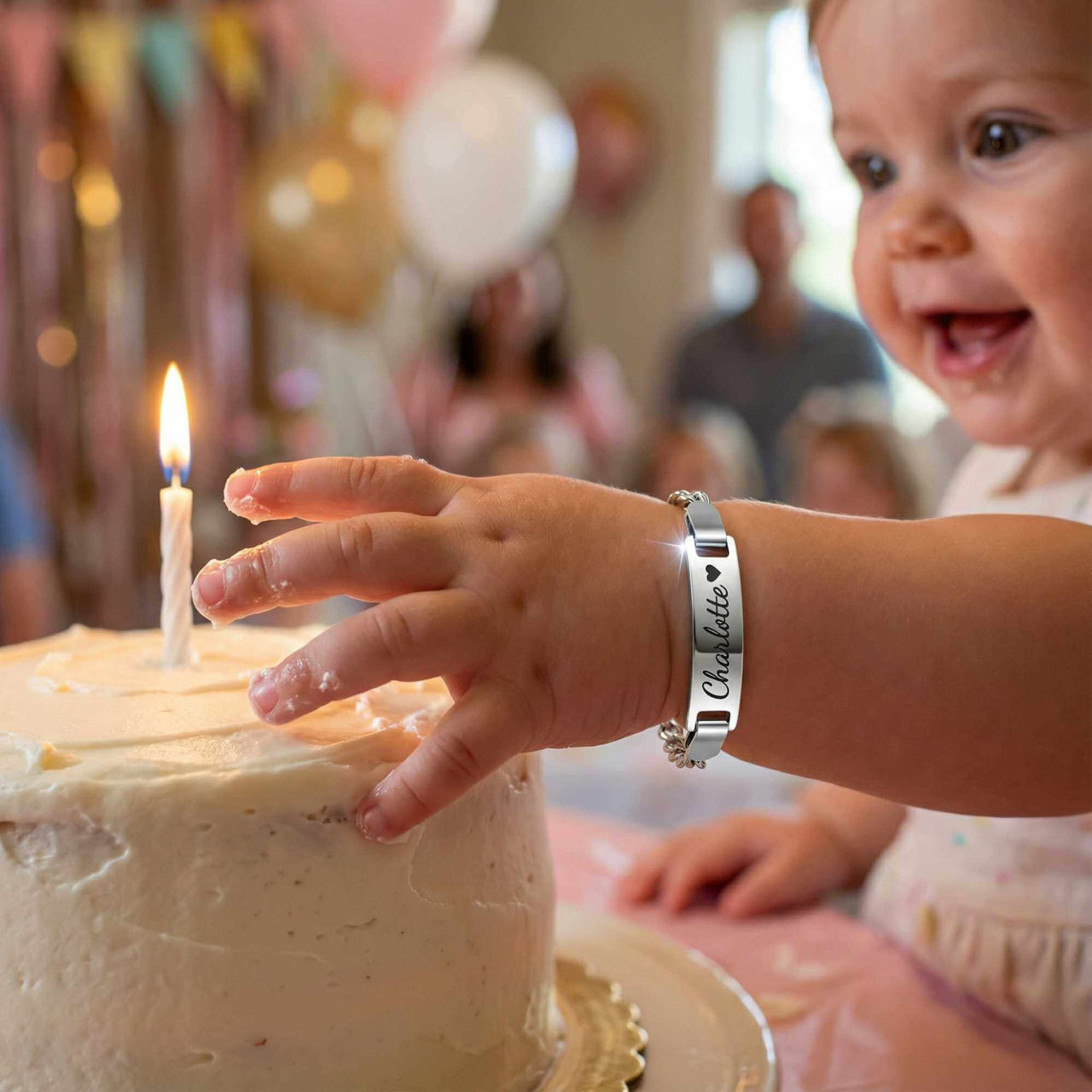 Infant Bracelet with personalized name on a child's wrist, celebrating a birthday with a cake.