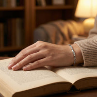 Thumbnail for Infinity Bond Matching Bracelet on a hand resting on an open book, showcasing love and connection by Brother & Sisters.