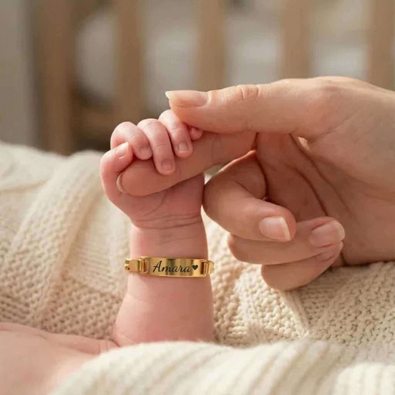 Infant Bracelet by Brother & Sisters featuring personalized name 'Amara' on a baby's wrist with a gentle hand.