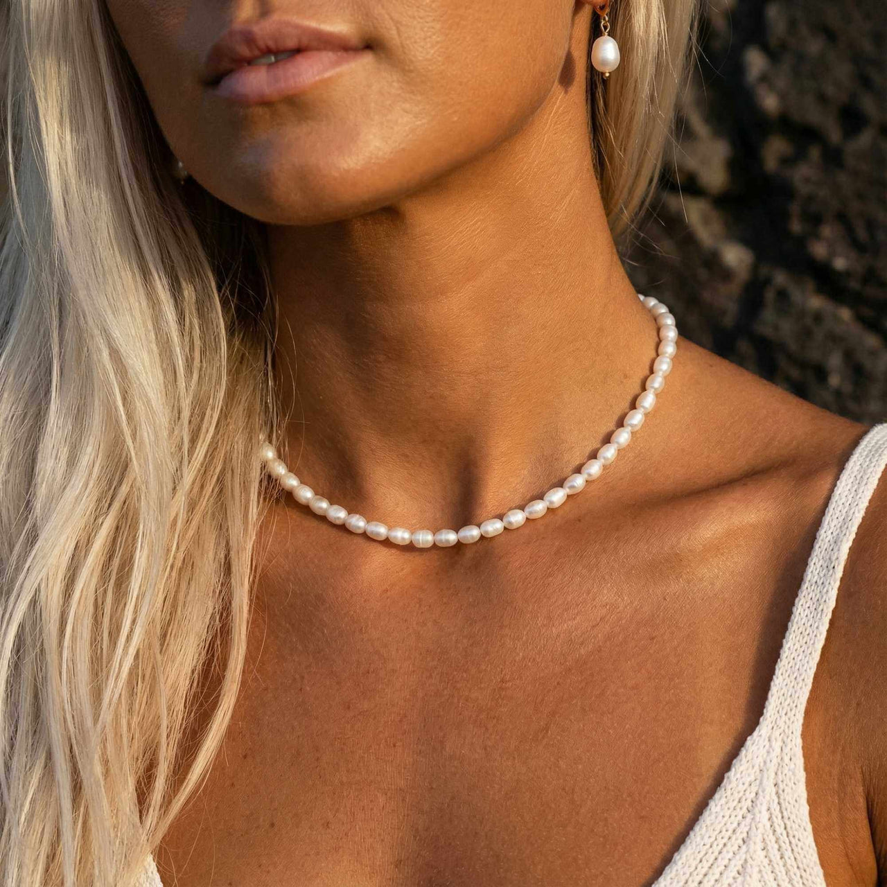 Freshwater pearl choker close-up — small baroque pearls at the throat with sun-kissed natural light, hypoallergenic everyday necklace