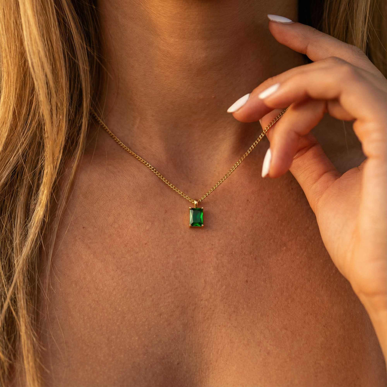 Emerald Pendant Necklace in gold setting worn by a woman, featuring vibrant emerald green stone by Brother & Sisters.