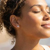 Thumbnail for Woman wearing Crystal Flower Stud Earrings, showcasing the tiny four-leaf design and elegant sparkle by Brother & Sisters.