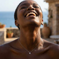 Thumbnail for Woman smiling while wearing Crystal Flower necklace by Brother & Sisters — dainty refined four-leaf signature