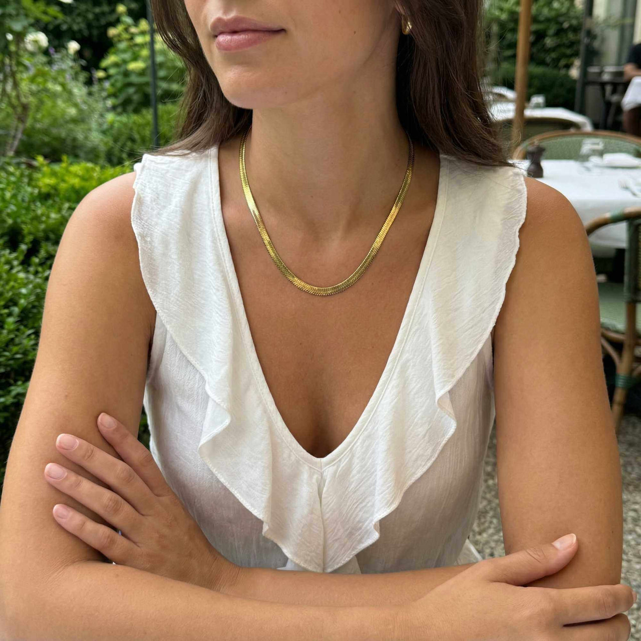 The Golden Statement necklace worn by a woman in a white dress, showcasing timeless elegance and modern edge by Brother & Sisters.