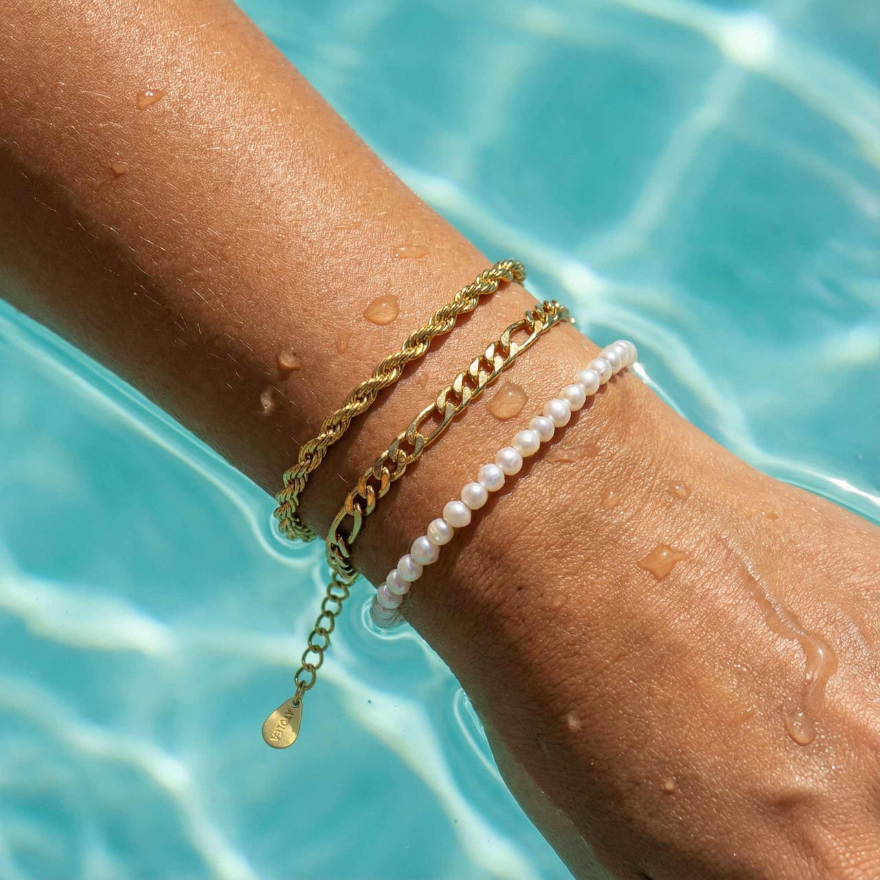 Calvi Rope Chain Bracelet stacked with other bracelets in water, showcasing its 18K gold PVD finish by Brother & Sisters.