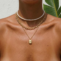 Thumbnail for Starlight Pendant Necklace by Brother & Sisters close-up on model, featuring gold tag pendant with starburst detail.