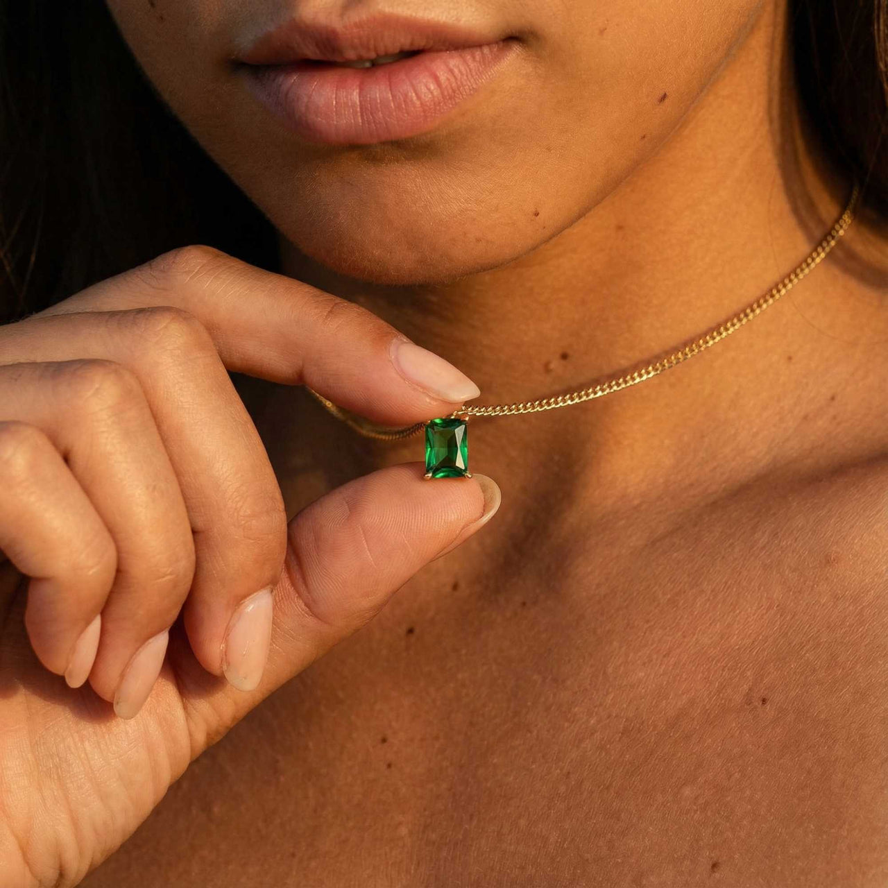 Emerald Pendant Necklace worn by a model, featuring a vibrant green emerald in a gold setting by Brother & Sisters.