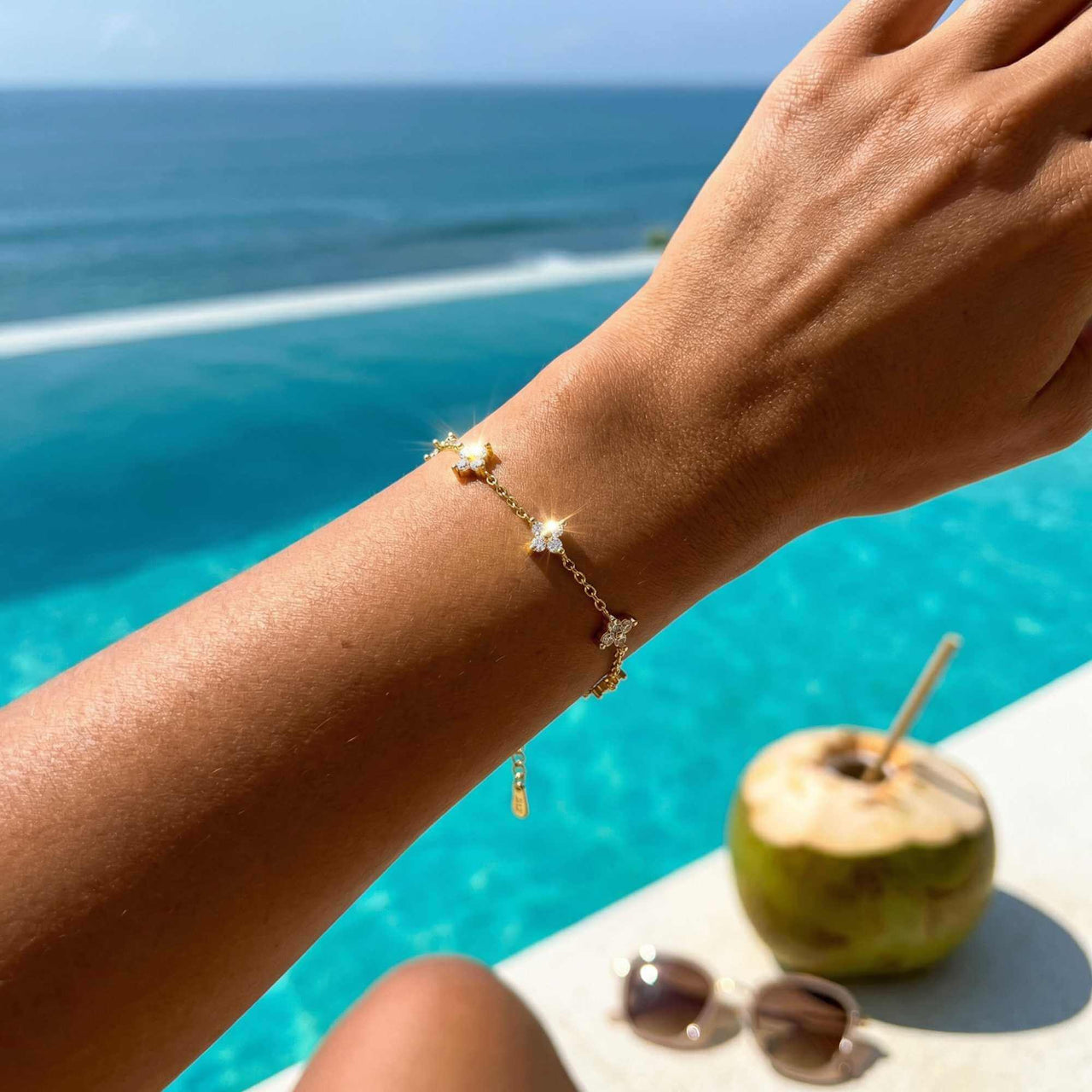 Crystal Flower Bracelet by Brother & Sisters featuring five sparkling crystal flowers on a wrist by the pool.
