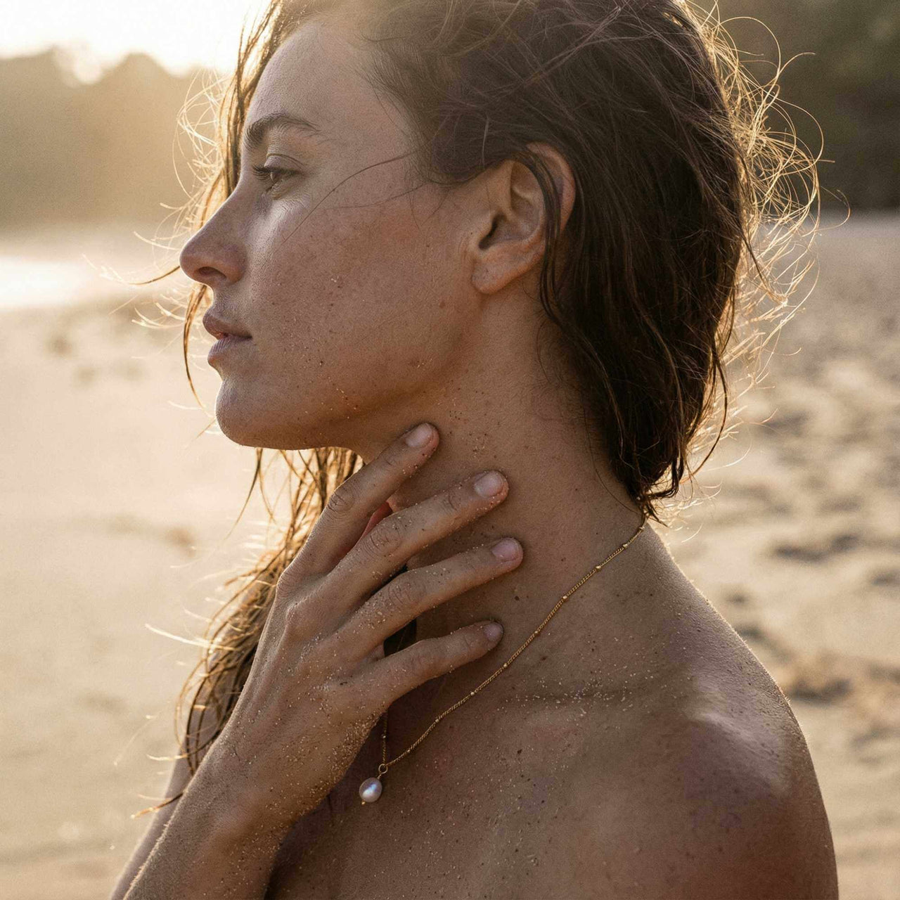 Model wearing Brother & Sisters Pearl Drop Necklace on the beach at sunset, showcasing its elegance and simplicity.