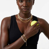 Thumbnail for Kauai Herringbone Bracelet worn with mixed necklaces and holding a tennis ball, by Brother & Sisters.