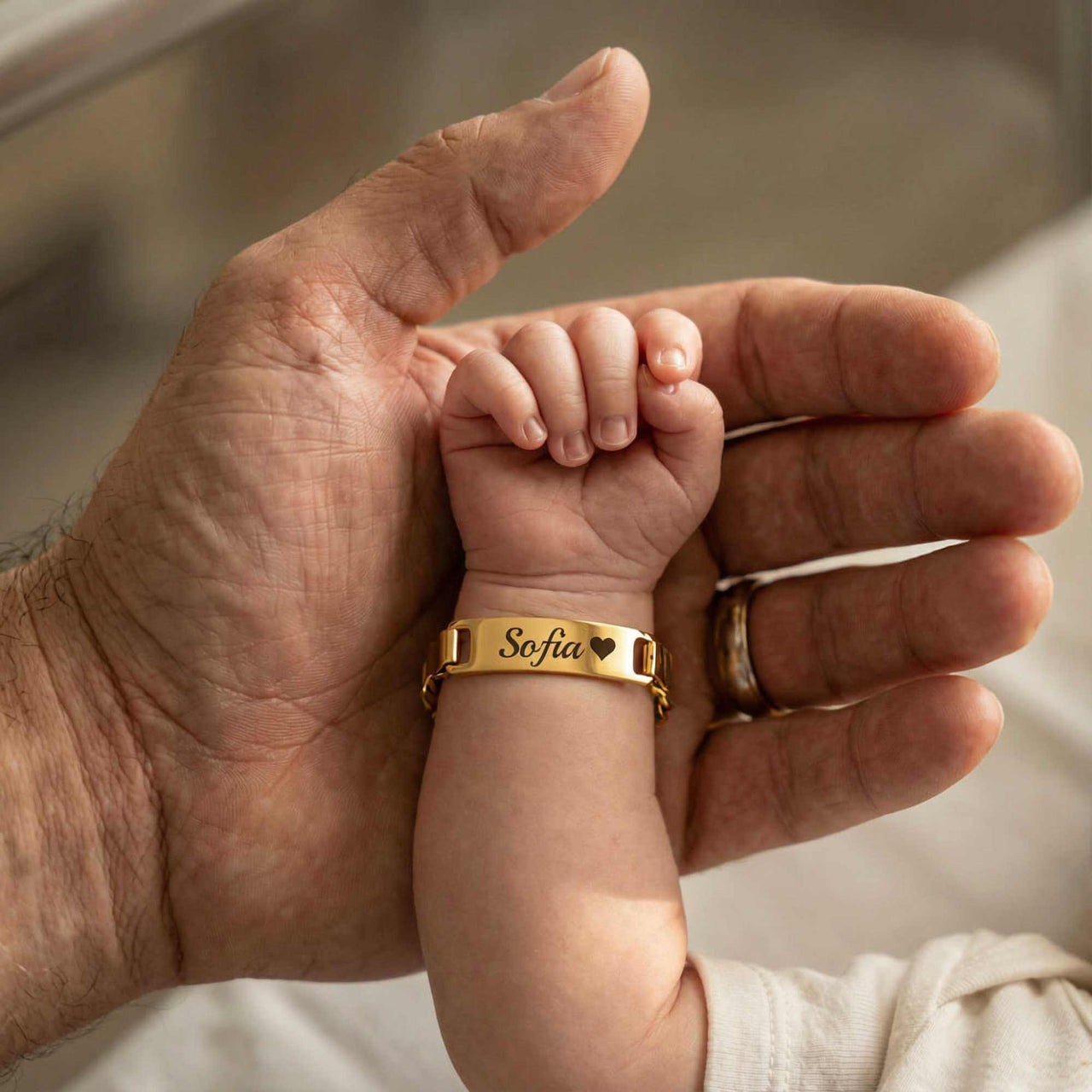 Infant Bracelet on baby's wrist with the name 'Sofia', held by a parent's hand, by Brother & Sisters.