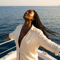 Thumbnail for A woman wearing a Dainty Pearl Choker enjoying the ocean breeze on a boat, showcasing the elegant design by Brother & Sisters.