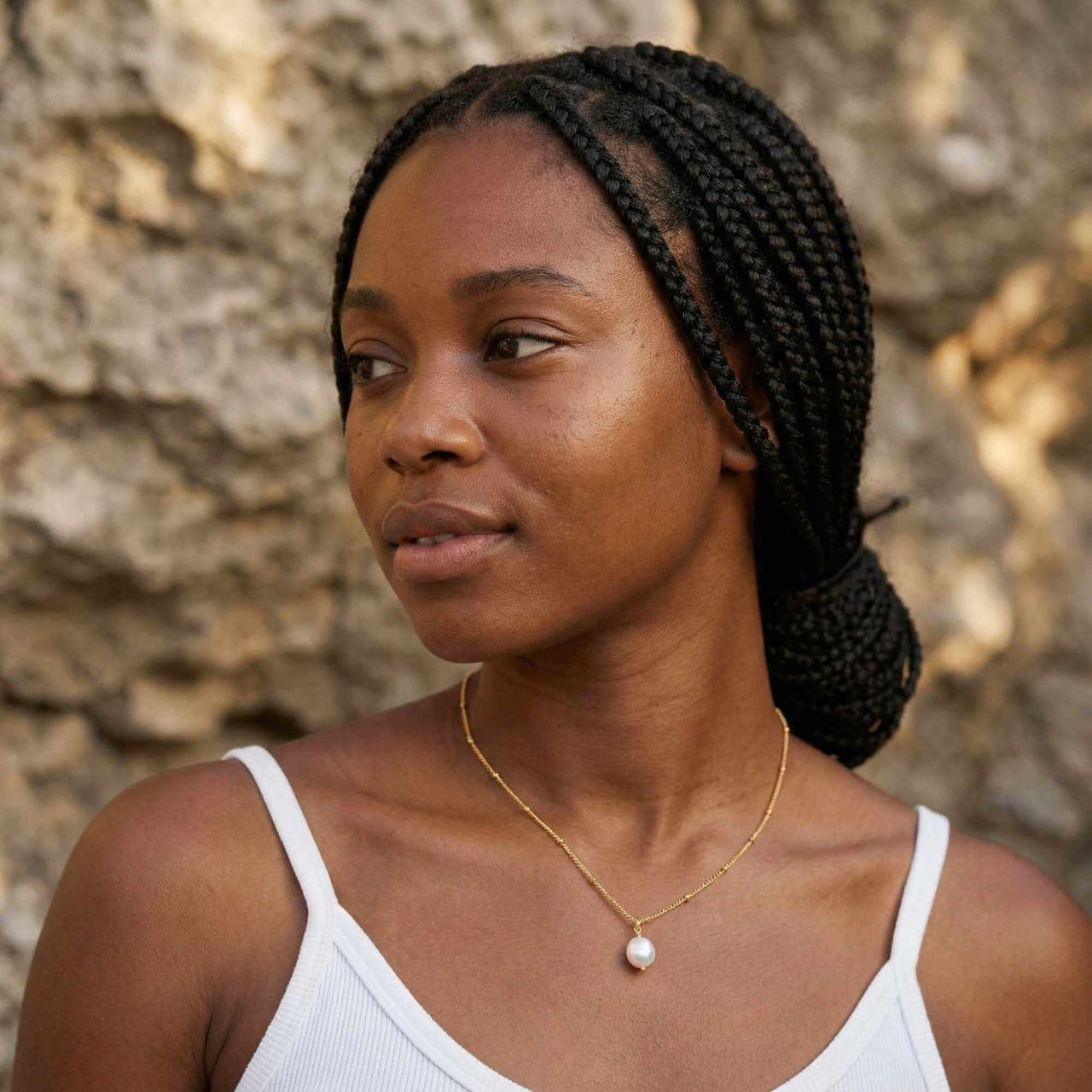 Pearl Drop Necklace worn by a woman with braided hair, showcasing its elegant design and lustrous pearl.