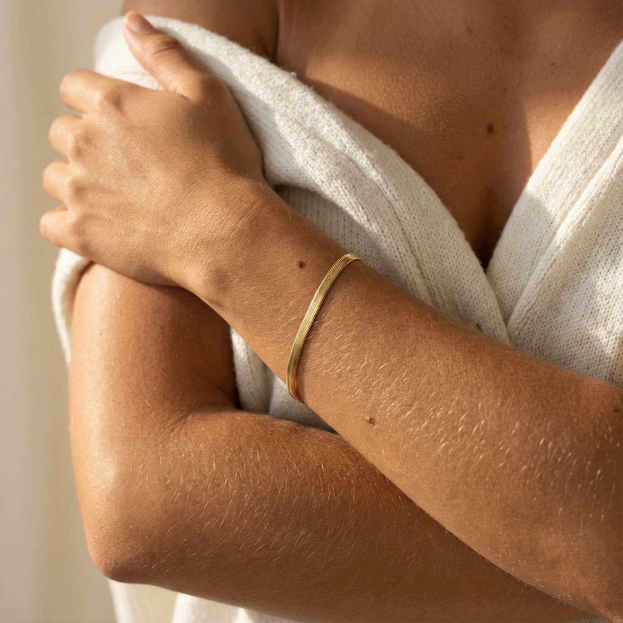 Kauai Herringbone Bracelet on a woman's wrist, showcasing its sleek design and 18K gold PVD finish by Brother & Sisters.