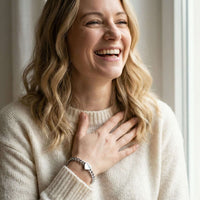 Thumbnail for A woman smiling while wearing a Love Couple Bracelet by Brother & Sisters, showcasing the polished heart on a Cuban link chain.