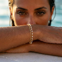 Thumbnail for Model showcasing the Double White Bracelet with a white enamel beaded chain and gold link by Brother & Sisters.