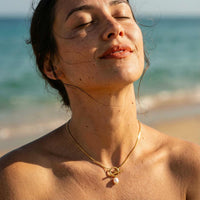 Thumbnail for Model wearing La Isla Pearl Toggle Necklace by Brother & Sisters on the beach, showcasing its unique sculptural clasp and pearl detail.