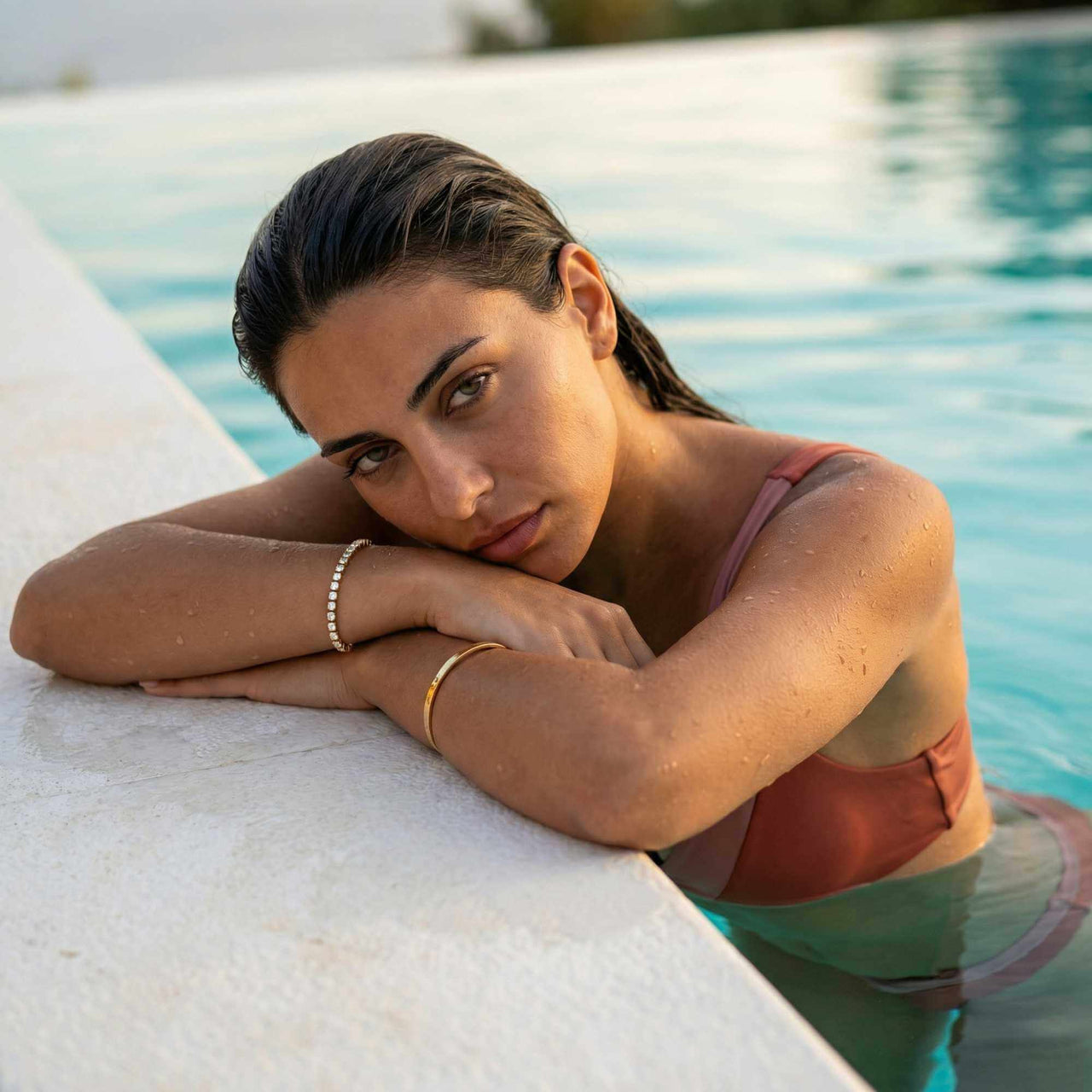 Model wearing a Tennis Bracelet by Brother & Sisters, relaxing by the pool in a swimsuit.