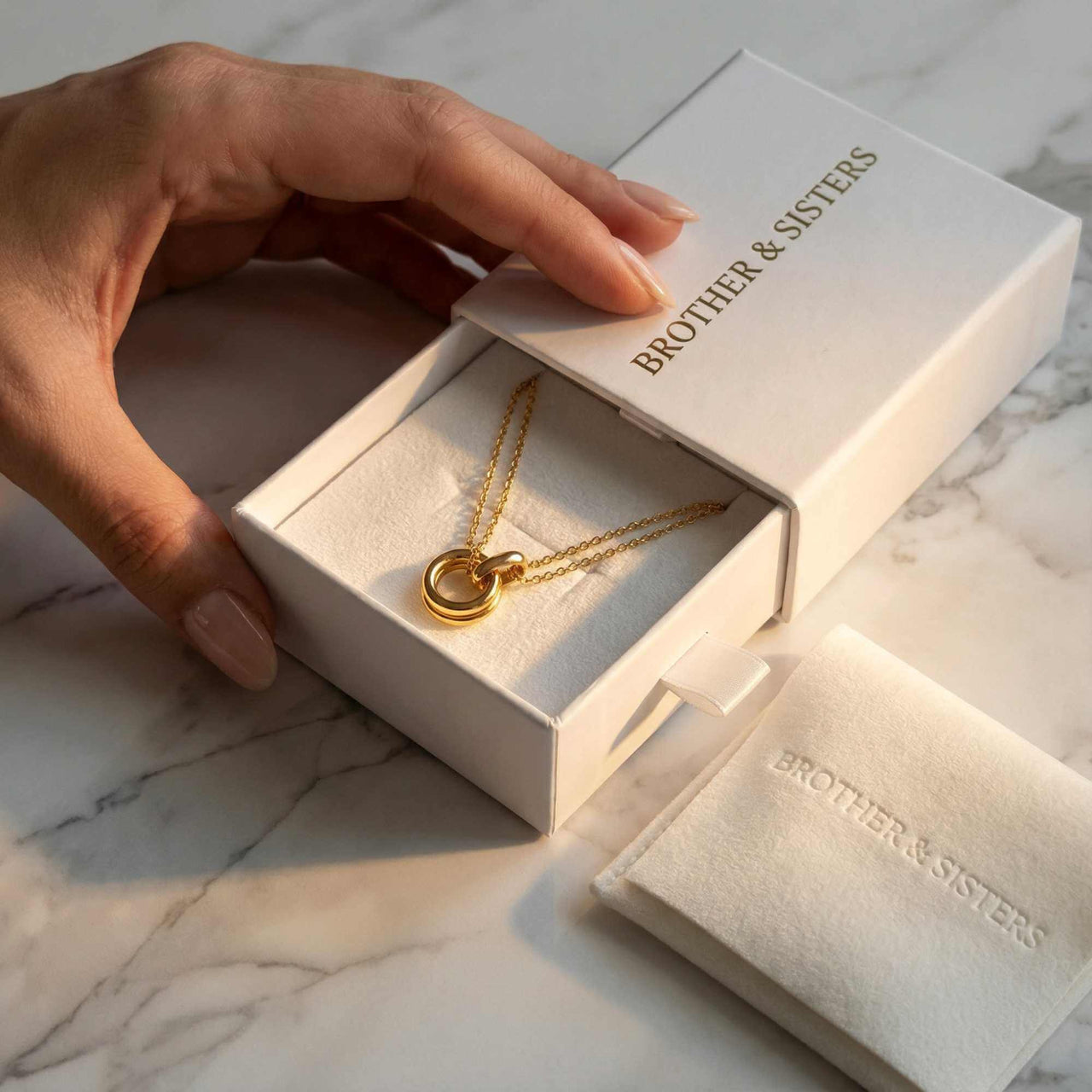 The Eternal Link necklace by Brother & Sisters, featuring interlocking circle pendant and gold chains in elegant packaging.