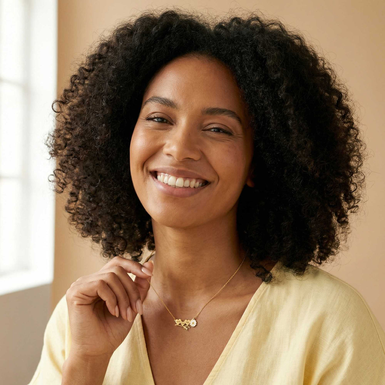 Daisy Name Necklace worn by a smiling woman, featuring connected hearts and a white enamel daisy. Crafted by Brother & Sisters.