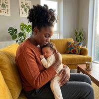 Thumbnail for Woman holding her sleeping baby on a couch, showcasing warmth and love in a cozy home setting.