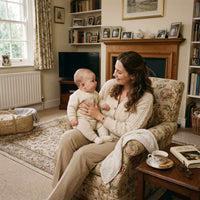 Thumbnail for Woman wearing Photo Projection Bracelet while holding her baby in a cozy living room, with warm tones and family photos.