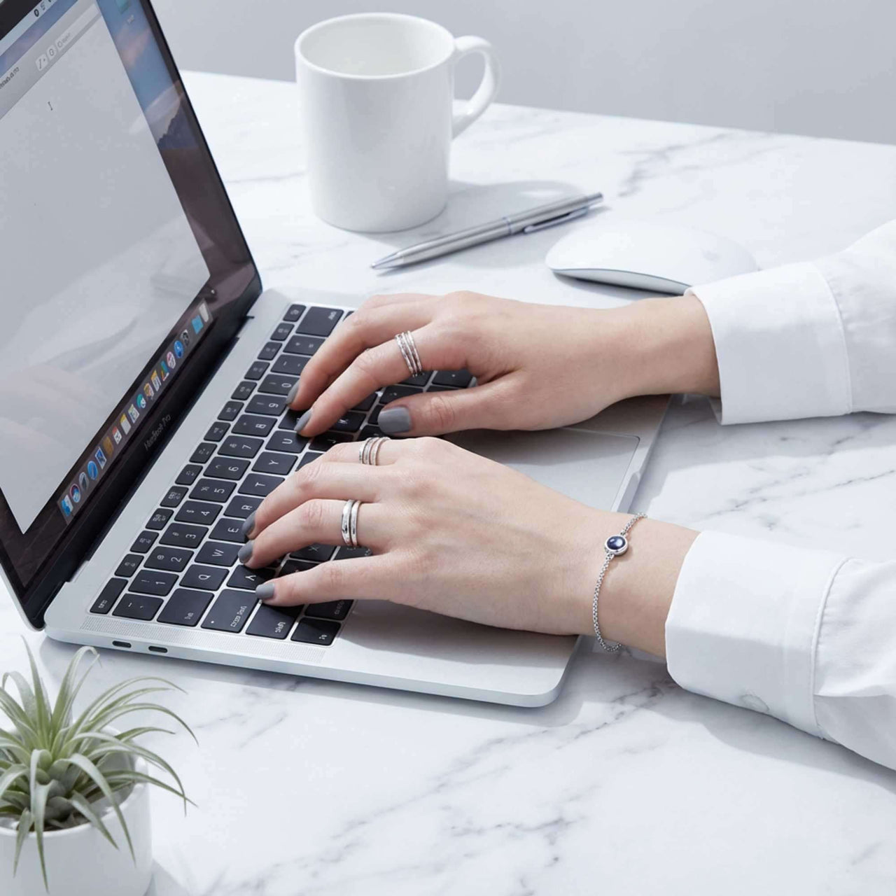 Photo Projection Bracelet worn by a woman typing on a laptop, showcasing its elegant design by Brother & Sisters.