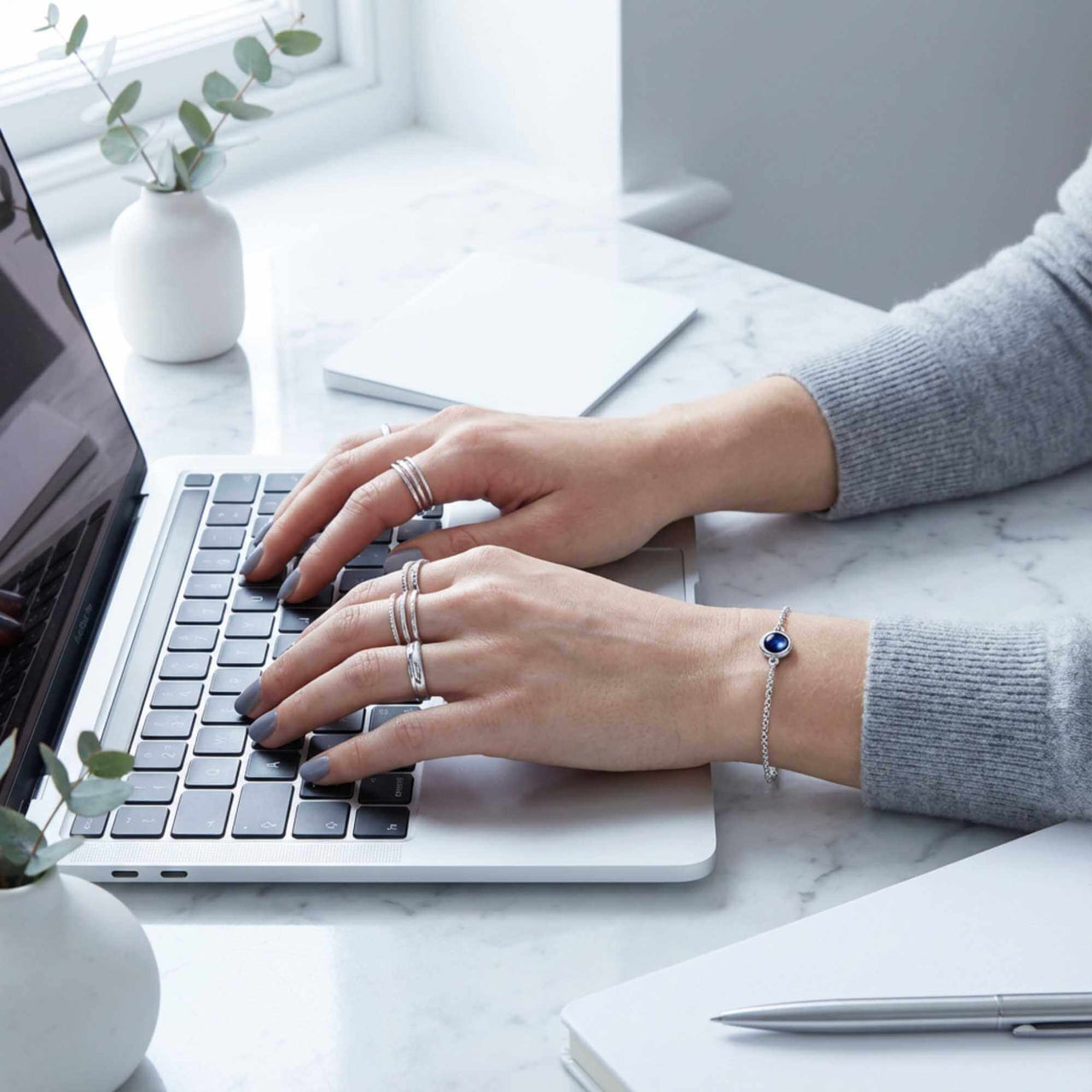 Photo Projection Bracelet by Brother & Sisters, featured on a woman’s wrist while typing on a laptop.