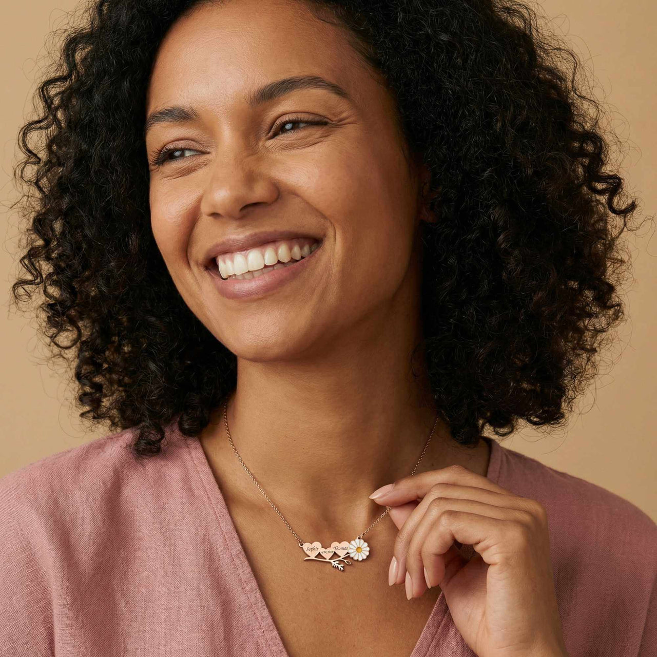 Daisy Name Necklace worn by a smiling woman, featuring engraved names in hearts and a white enamel daisy.