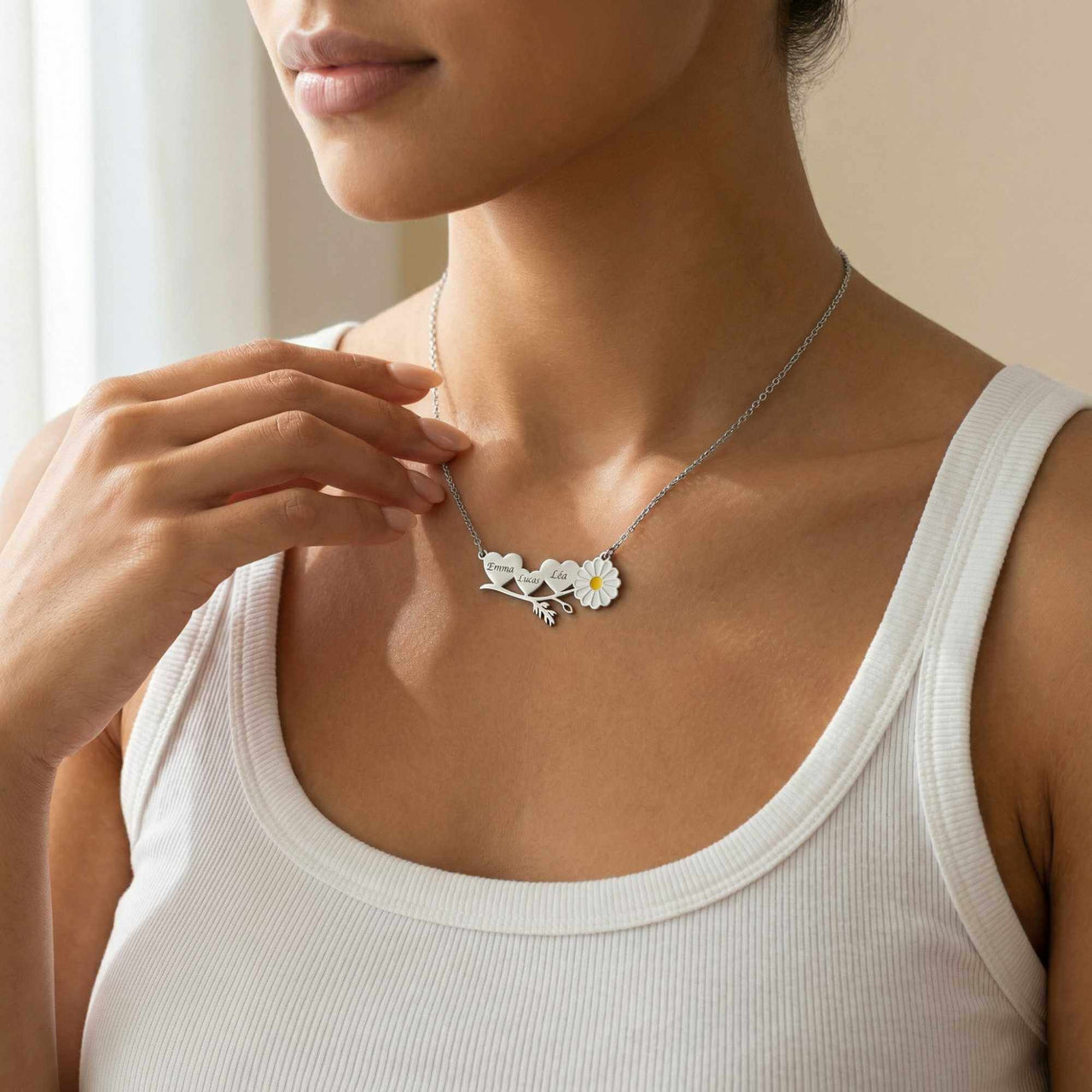 Daisy Name Necklace by Brother & Sisters featuring three hearts and a white enamel daisy worn by a woman.
