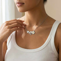 Thumbnail for Daisy Name Necklace by Brother & Sisters featuring three hearts and a white enamel daisy worn by a woman.