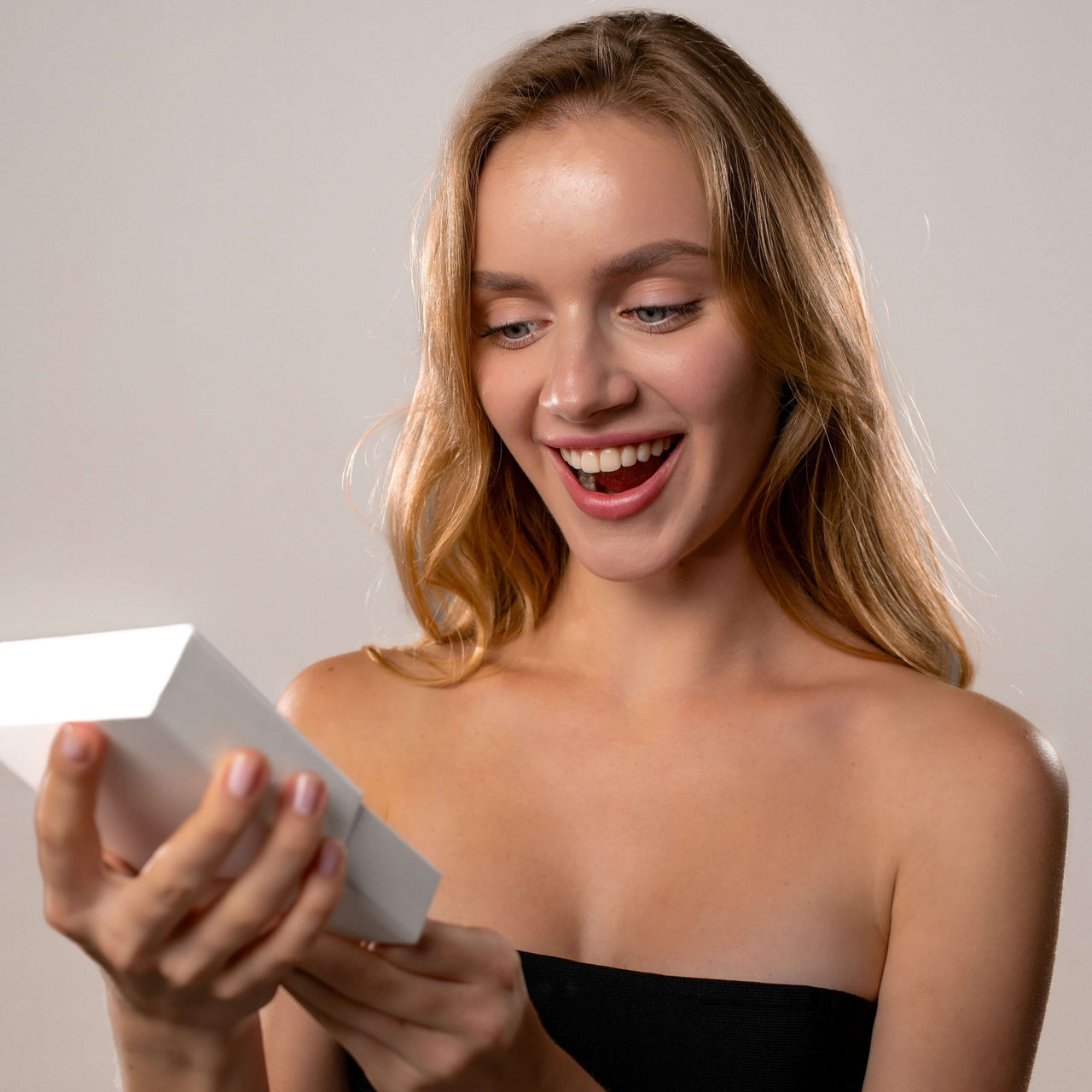 Woman excitedly opening a gift box, showcasing the Angel Photo Bracelet by Brother & Sisters.