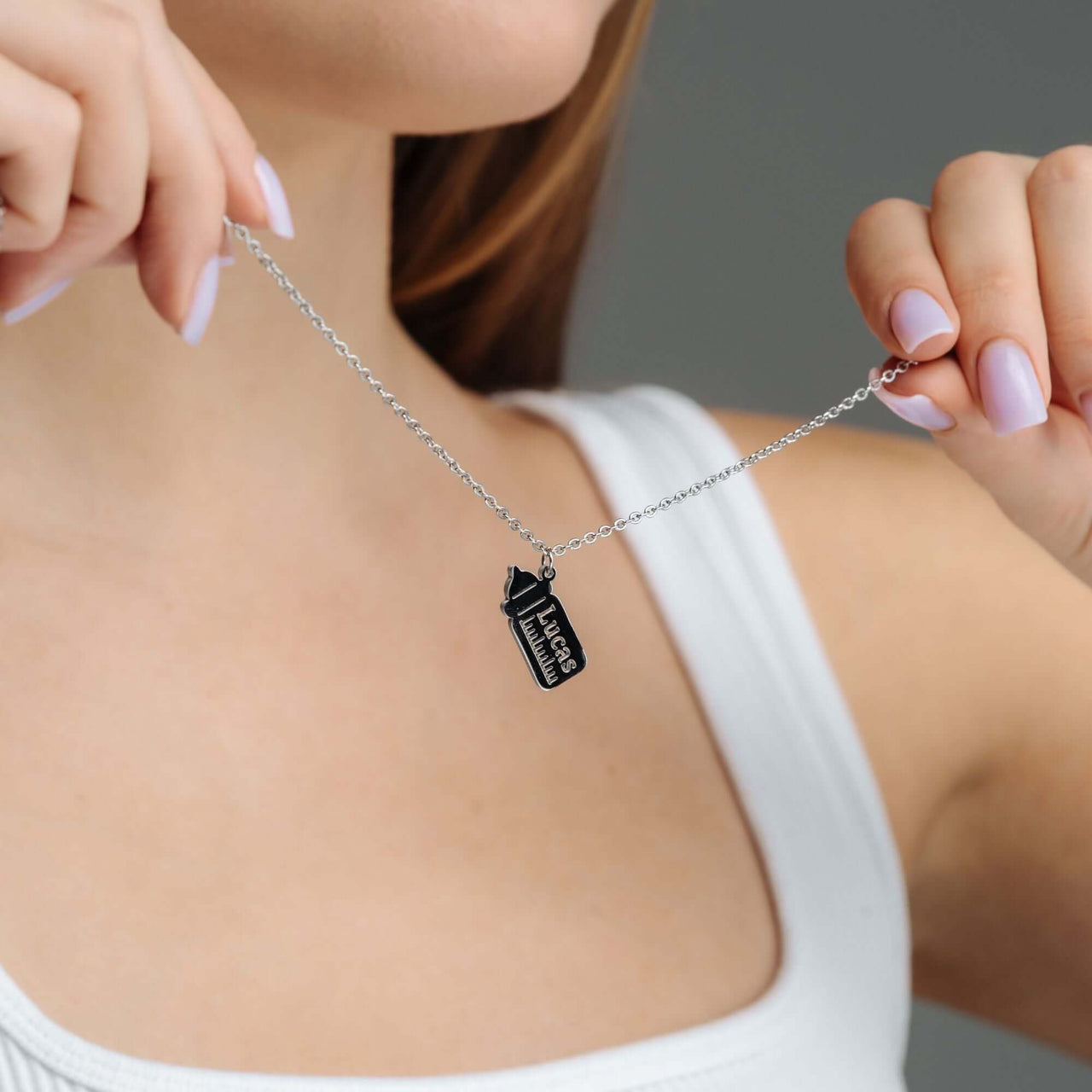 Baby Bottle Name Necklace held by a woman, showcasing personalized jewelry from Brother & Sisters.