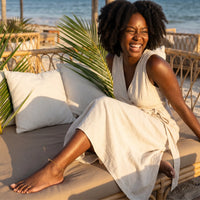 Thumbnail for A joyful woman wearing a linen dress and Beaded Station Anklet, enjoying beach vibes by the ocean, from Brother & Sisters.