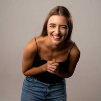 Thumbnail for Smiling woman in casual attire expressing joy and laughter against a neutral background.