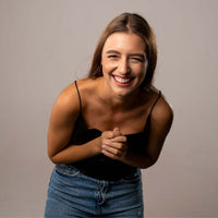 Thumbnail for Smiling woman wearing a black top and jeans, showcasing joy and positivity in a cheerful portrait.
