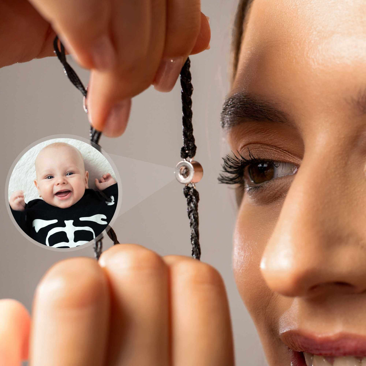 A woman holding the Black Photo Bracelet featuring a personalized photo of a smiling baby, showcasing its sentimental design by Brother & Sisters.