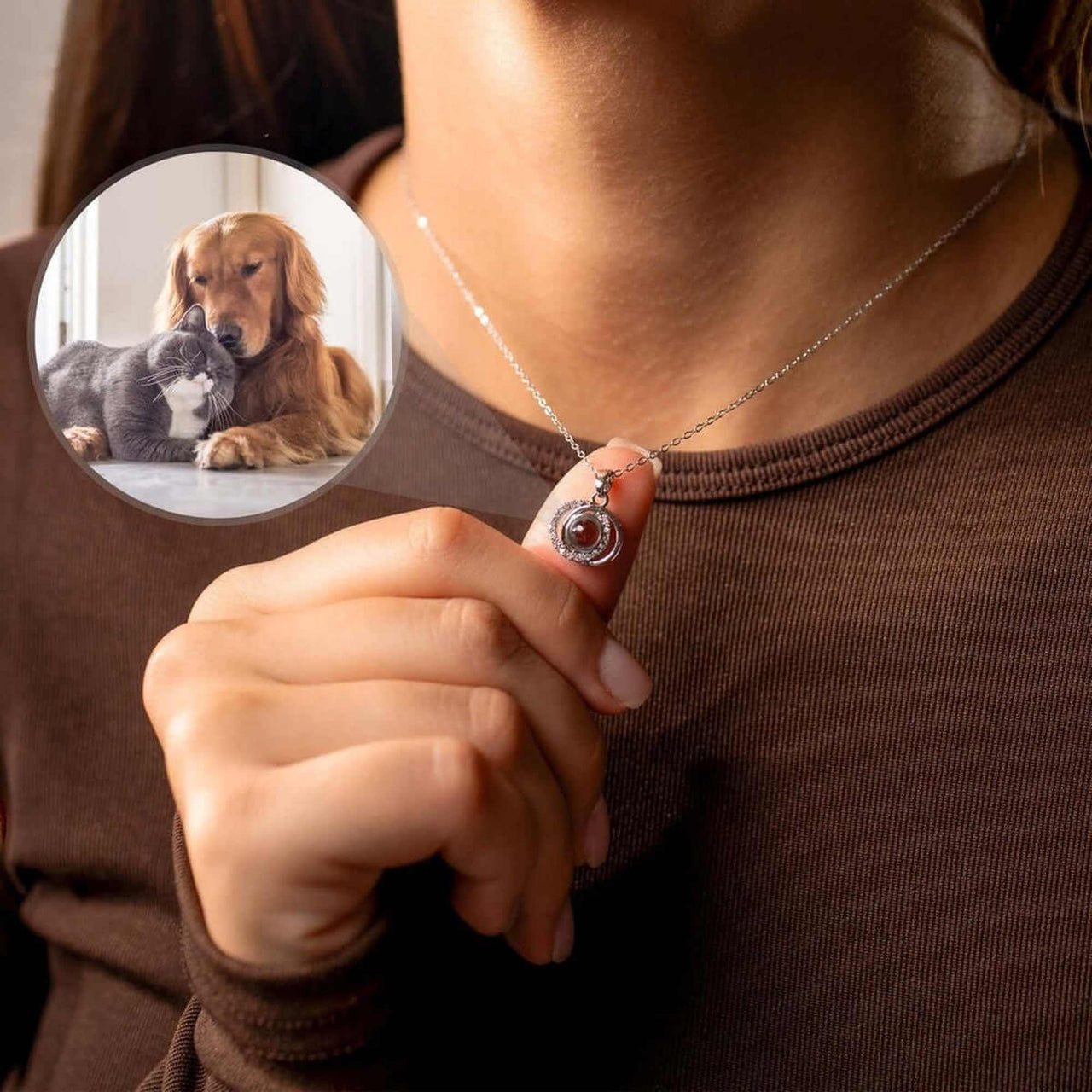 A person holding the Duo Photo Necklace by Brother & Sisters, showcasing a personalized photo of a dog and cat.