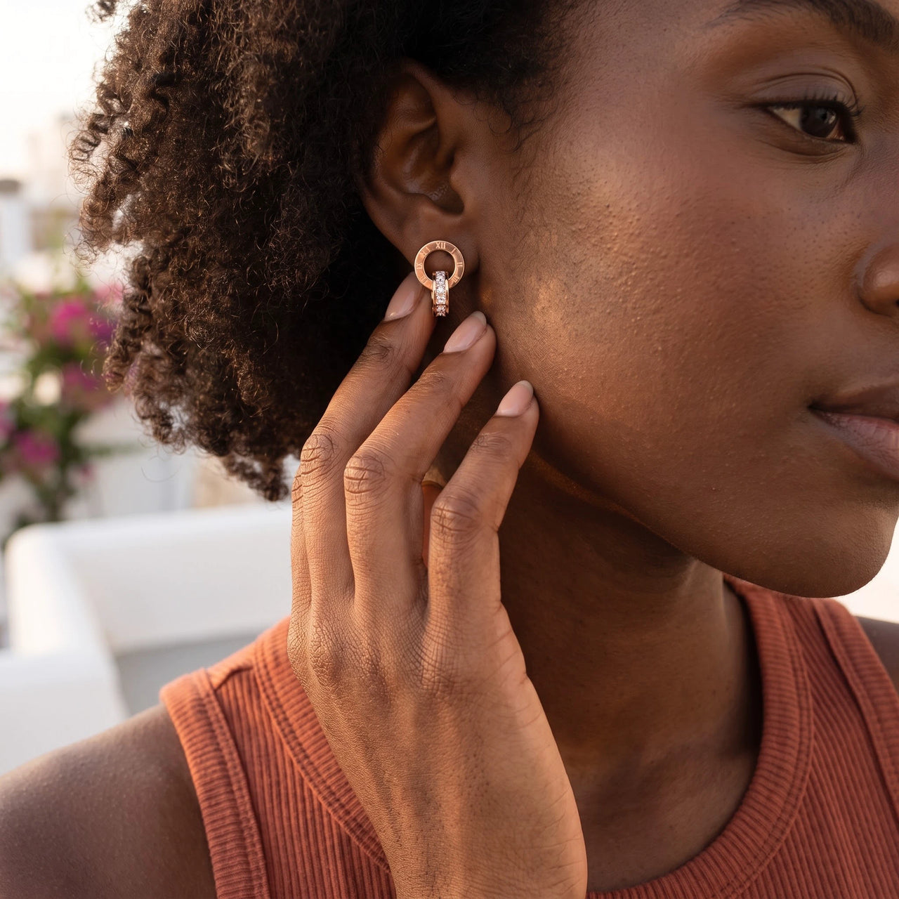 Woman gently touching her rose gold huggie hoop earrings | SKU: 11137578-rose-gold